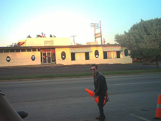 a man, enthusiastically humping the air while holding an orange road cone between his legs in a rather phallic maner. 